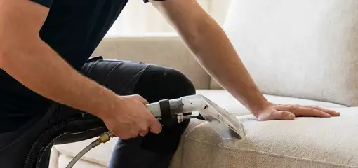 Professional upholstery cleaner deep-cleaning a fabric sofa with a handheld extraction tool, Bradenton, FL.